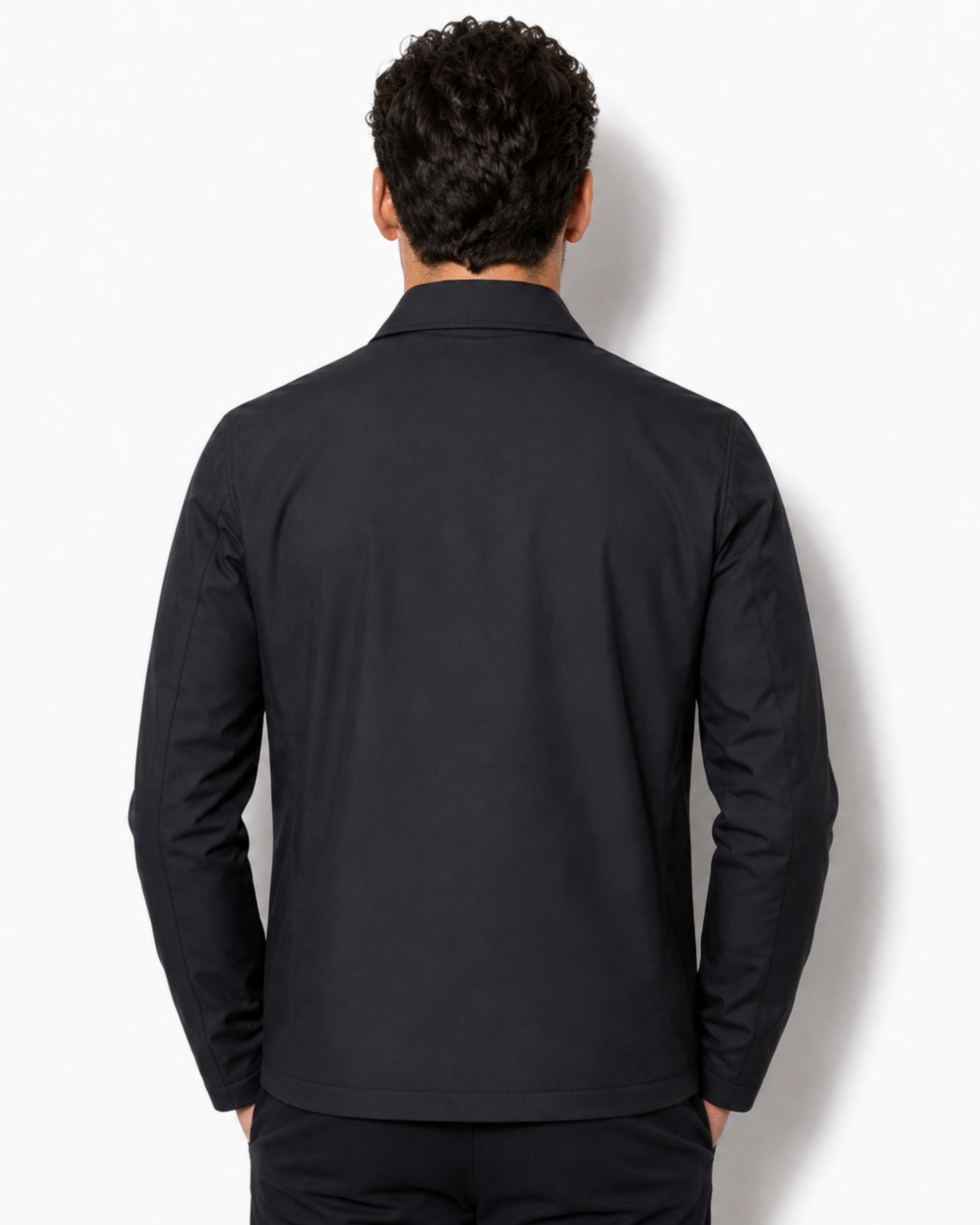Back view of a male model wearing the minimalist black tailored outerwear jacket.