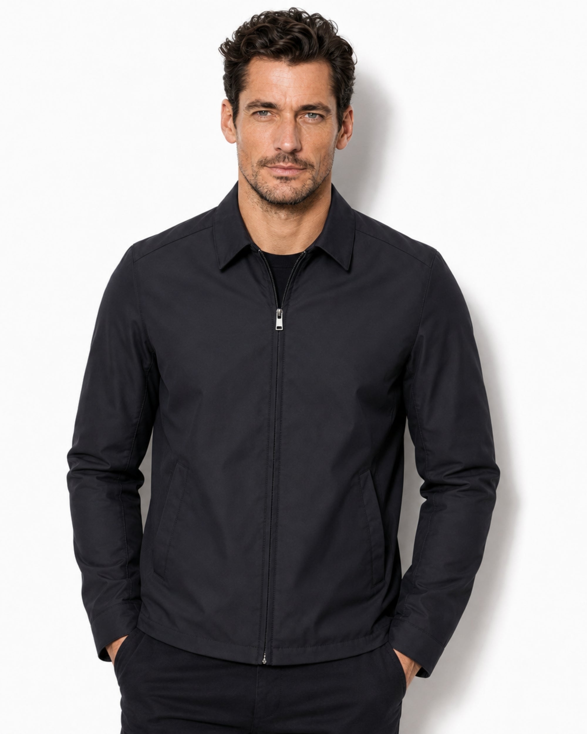 Front studio view of a male model wearing the men's luxury black lightweight Harrington jacket over a black t-shirt."